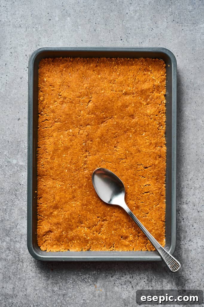 A cookie crust evenly pressed into a baking dish, ready for the next layer.