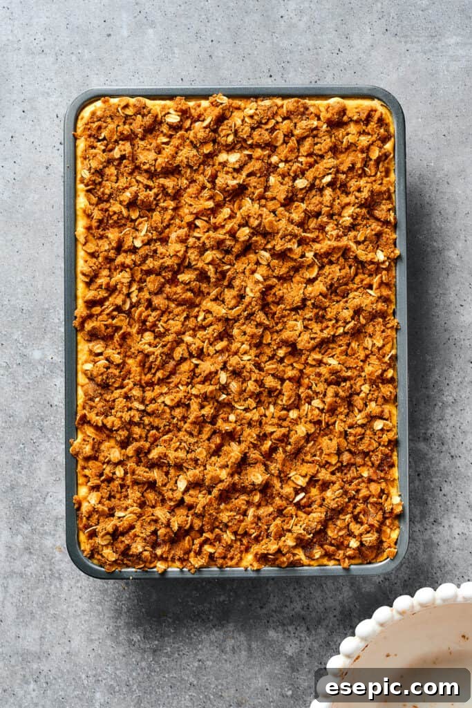 An unbaked baking dish of pumpkin bars, generously topped with streusel crumbs.