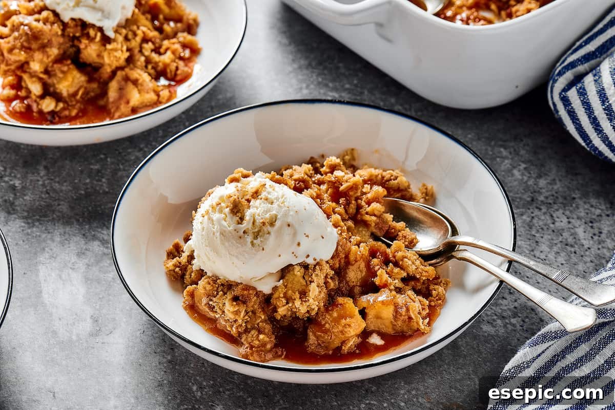 Three dessert bowls filled with warm apple crisp, each topped with a scoop of melting vanilla ice cream and a swirl of golden caramel sauce, ready to be enjoyed.