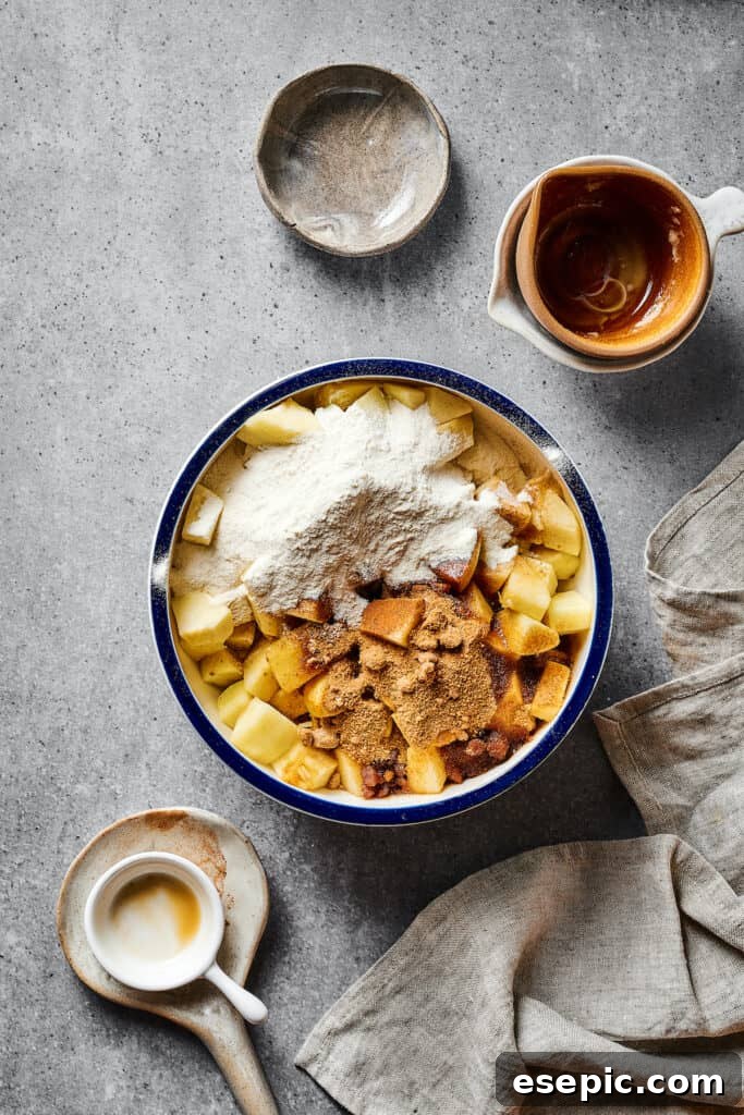 A large bowl of chopped apples with flour, butter, spices, and other ingredients mixed in. Preparing the apple crisp filling.