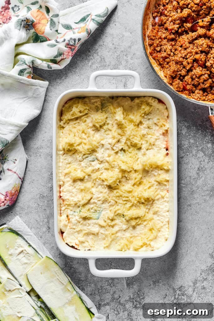 A generous sprinkling of shredded mozzarella cheese over the layered ingredients in a baking dish, adding to the cheesy goodness.