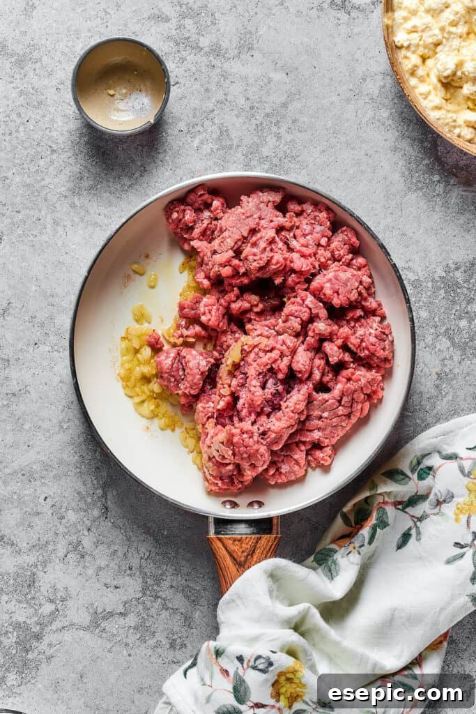Garlic, onions, and ground beef cooking in a skillet, forming the base of the delicious meat sauce.