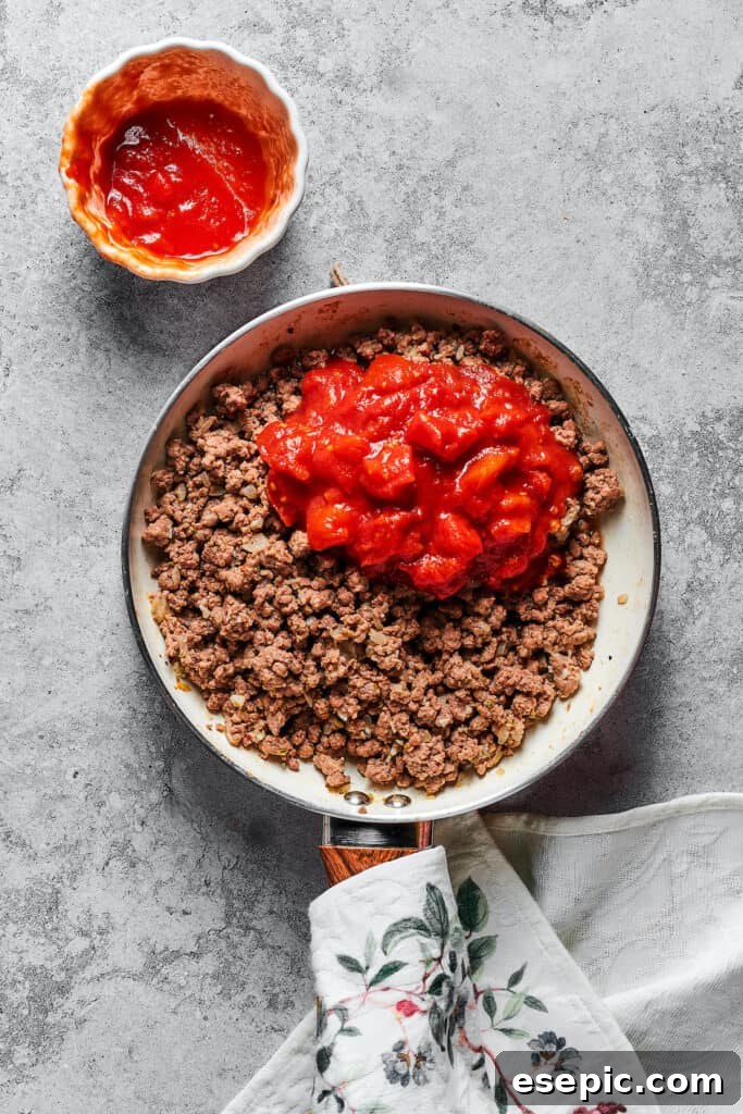 Rich meat sauce ingredients simmering together in a skillet, creating a flavorful base for the lasagna.