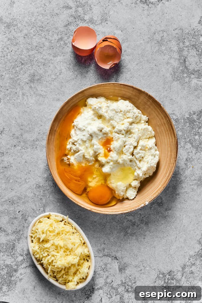 Cottage cheese, Parmesan cheese, eggs, and other cheese filling ingredients ready in a bowl, with a smaller bowl of shredded mozzarella nearby.