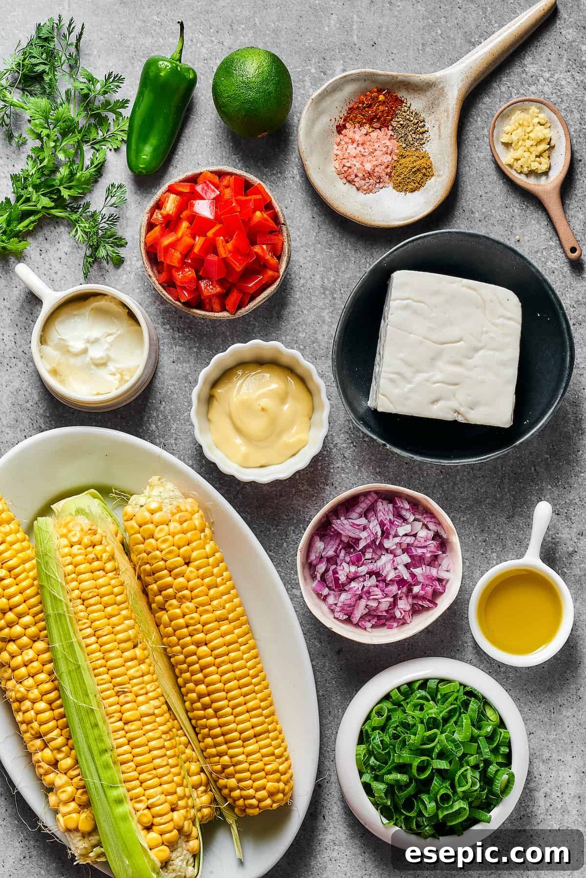 Mexican Street Corn Salad is a mouthwatering dish that’ll have everyone begging for the recipe! Fresh corn kernels in a killer creamy sauce. From top left: Cilantro, jalapeno, spices, minced garlic, sour cream, red bell pepper, mayonnaise, goat cheese, fresh corn, red onion, olive oil, chopped green onion.