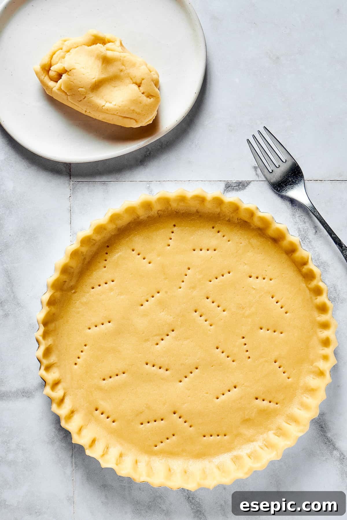 Pie dough pressed into a pie dish with the edges trimmed. The crust has been pricked with a fork.