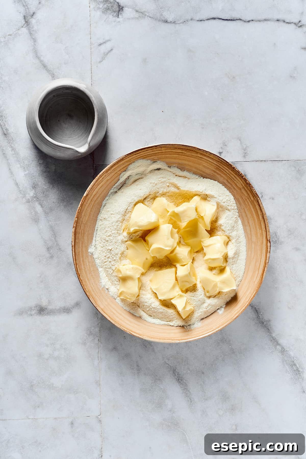 Butter being added to dry baking ingredients.