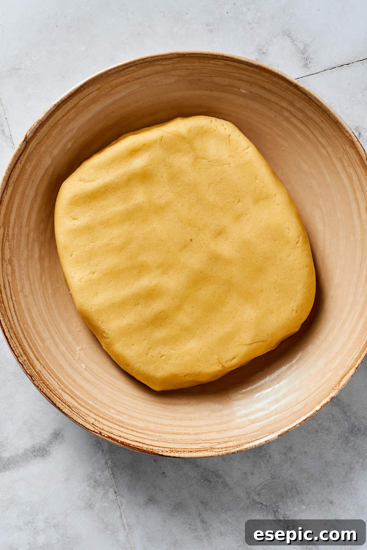 A flattened piece of pie dough in a mixing bowl.
