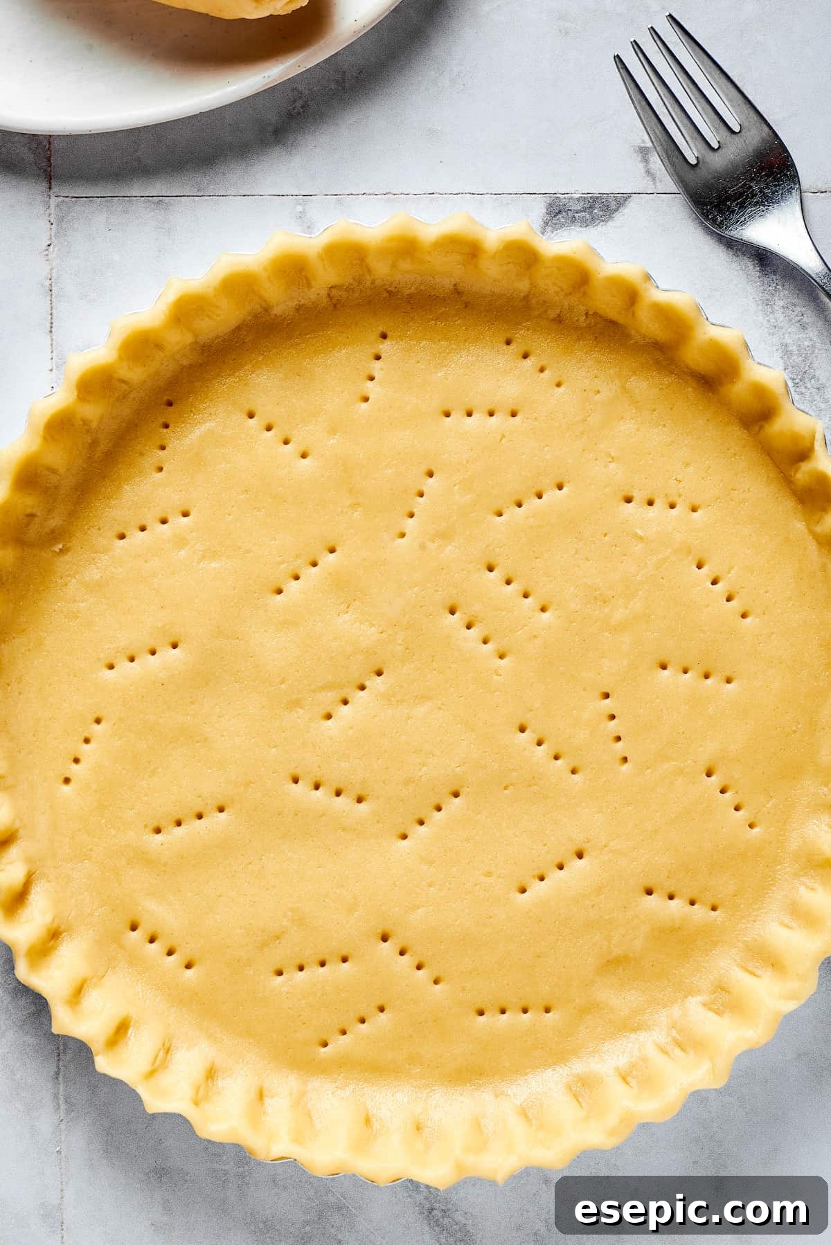 A pristine, beautifully shaped homemade pie crust resting in a metal pie plate, ready for baking.