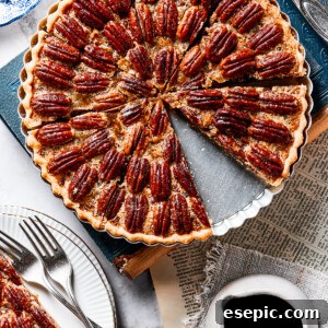 A slice of pecan pie on a small serving dish, next to the larger pie.