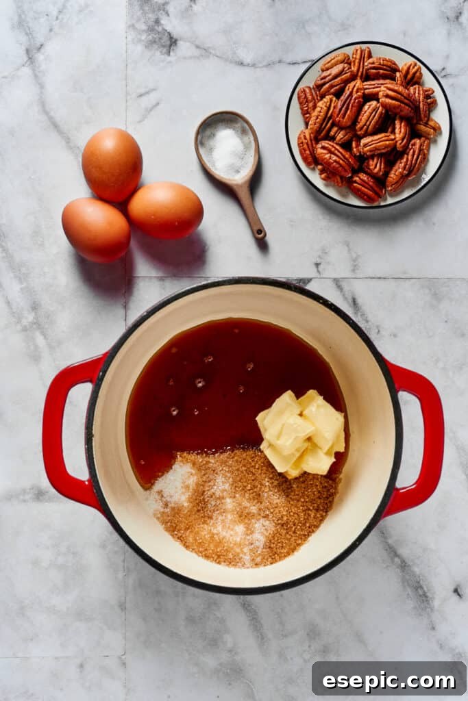 A heavy-bottomed saucepan containing butter, sugar, and maple syrup, with fresh eggs, salt, and pecans arranged nearby, ready for pie making.