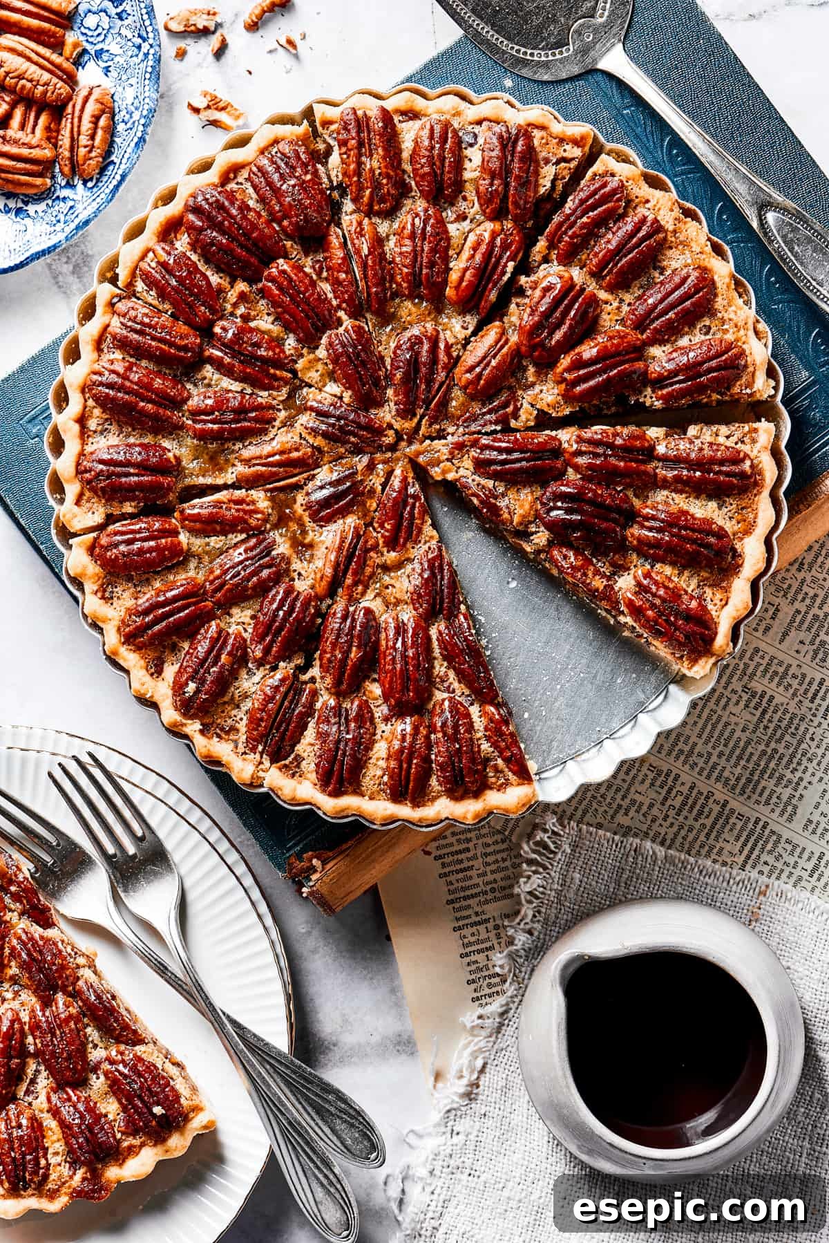 A single slice of pecan pie, perfectly cut and placed on a small white serving dish, positioned next to the remainder of the pie in its baking dish.