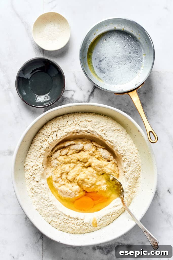 The Ultimate Homemade Pierogi Guide 4 Pierogi dough ingredients, including flour, salt, butter, warm water, and egg, prepared in a mixing bowl.