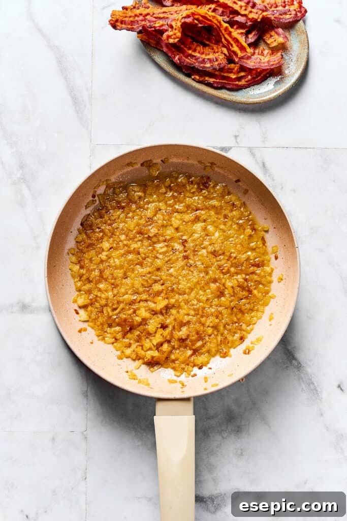 The Ultimate Homemade Pierogi Guide 11 Sweet caramelized onions glistening in butter in a skillet, with crispy bacon crumbles waiting nearby on a plate.