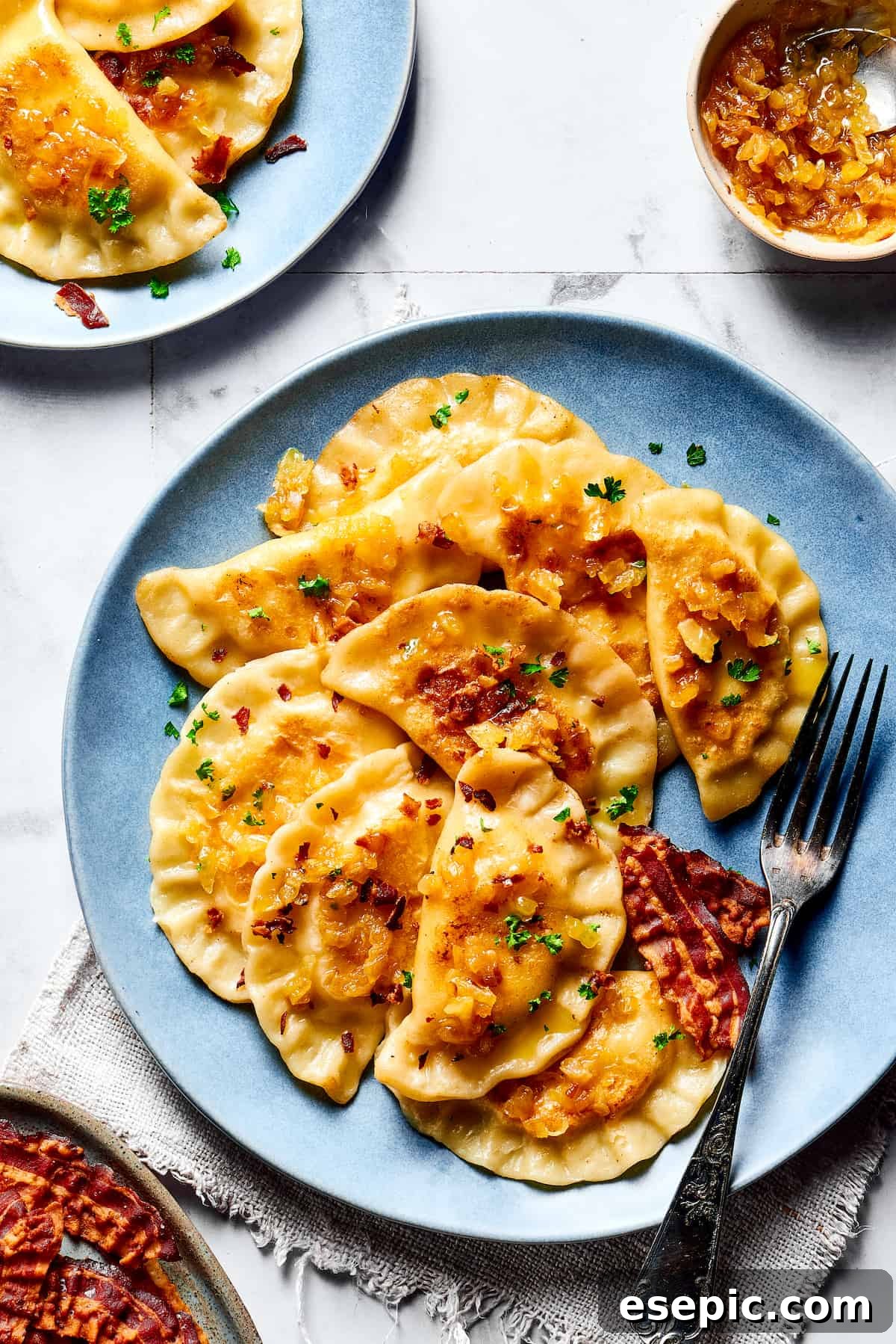 Finished Homemade Pierogi with Caramelized Onions and Crispy Bacon A vibrant plate of freshly cooked pierogi topped generously with golden caramelized onions and crisp bacon bits, ready to serve.