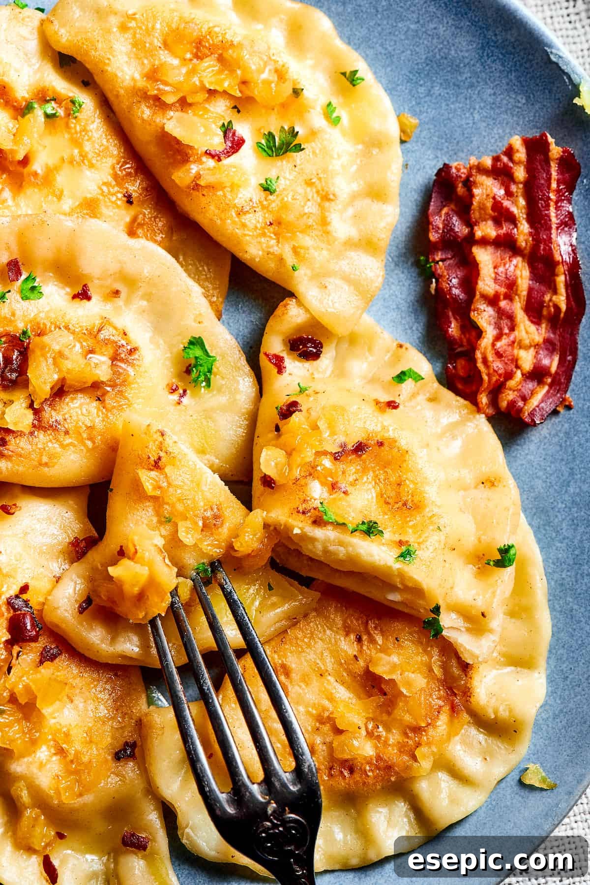 Cutting into a Homemade Pierogi to Show the Filling A fork cutting into a freshly made, warm potato and cheese pierogi, revealing its tender dough and creamy filling.