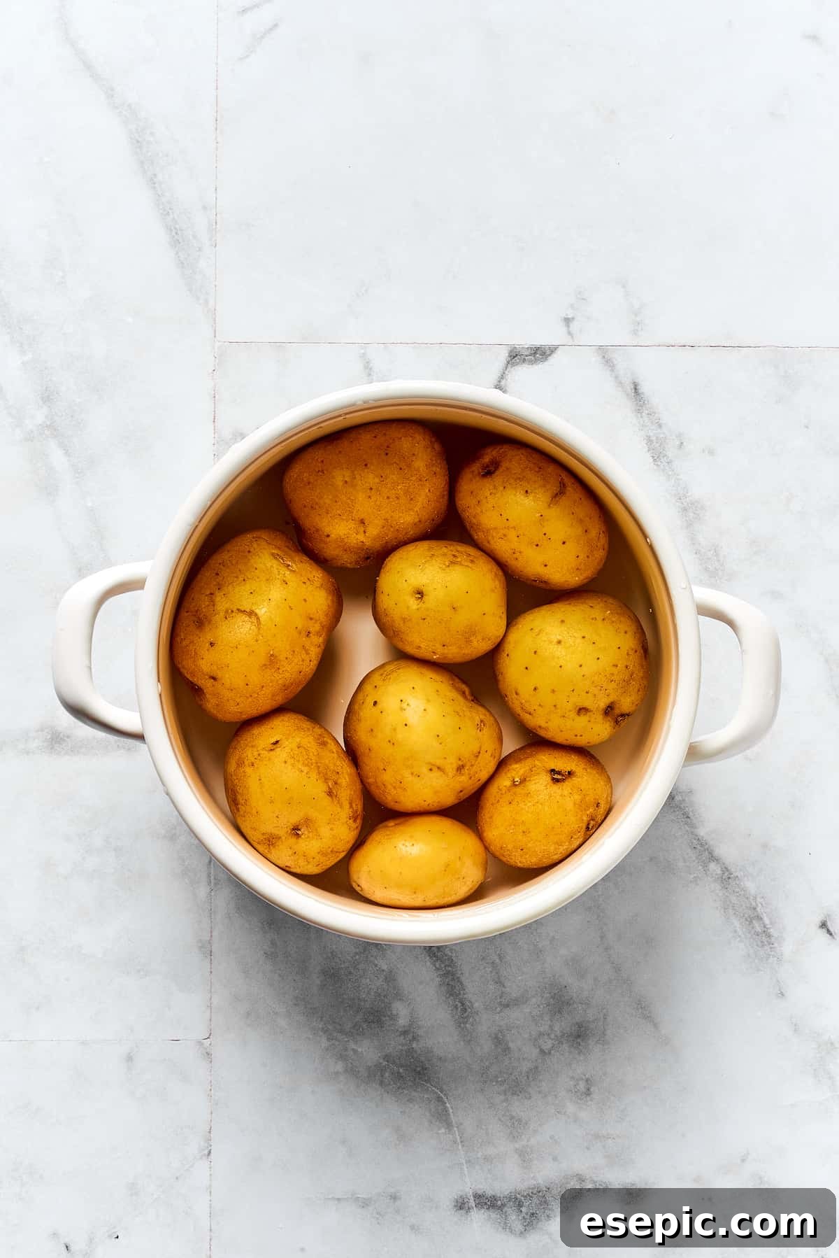 Potatoes Cooking for Pierogi Filling Yukon Gold potatoes boiling in a pot on the stovetop, covered with a lid slightly ajar.