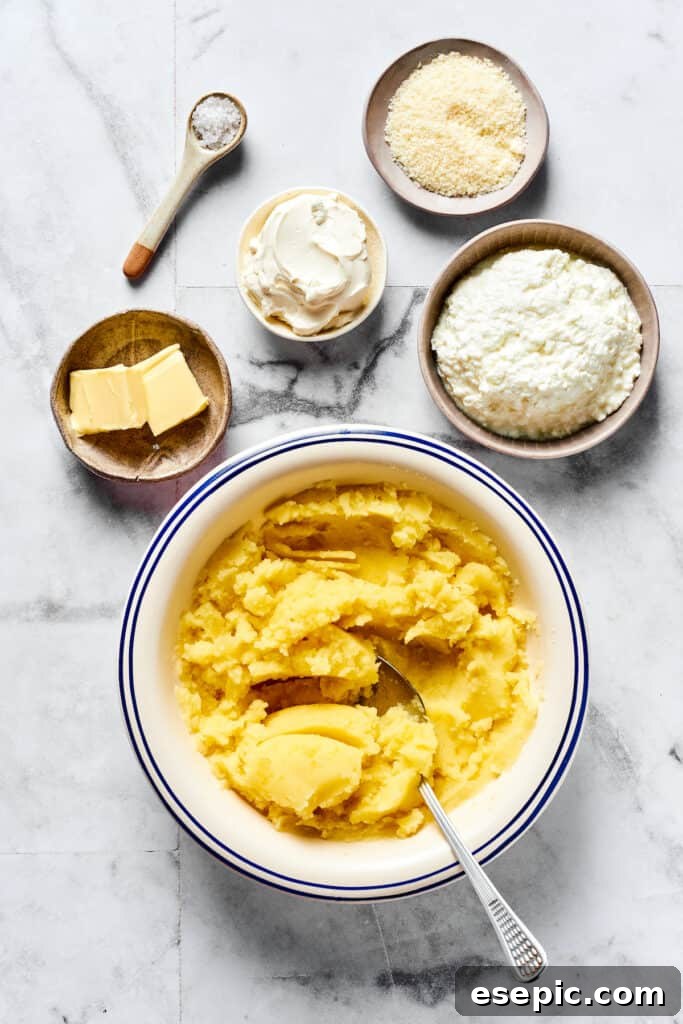 The Ultimate Homemade Pierogi Guide 2 Mashed potatoes in a bowl with separate dishes of cottage cheese, cream cheese, Parmesan, butter, and salt nearby.