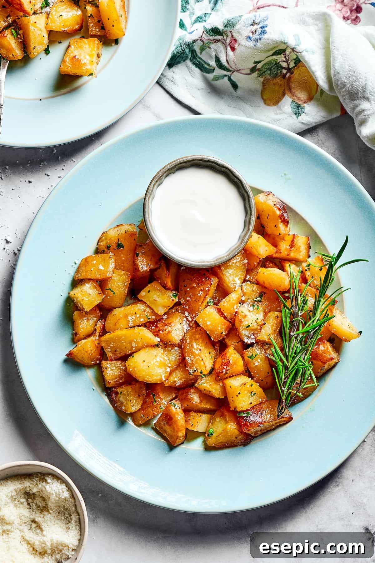 Seasoned roasted potatoes served with a small cup of creamy Greek yogurt sauce.