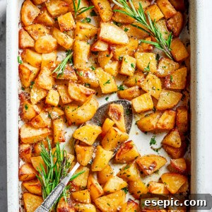 A large baking dish full of baked, seasoned potato pieces, garnished.