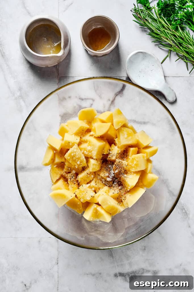 Raw potatoes and seasonings thoroughly mixed in a large mixing bowl.
