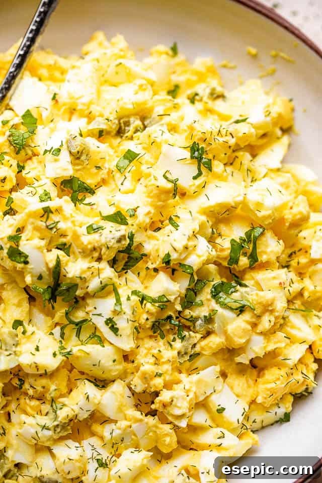 egg salad in a bowl topped with fresh parsley