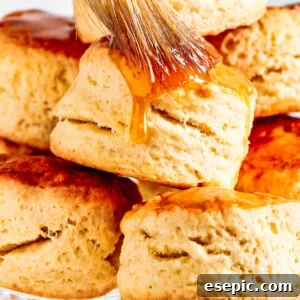 Brushing maple syrup on top of biscuits.