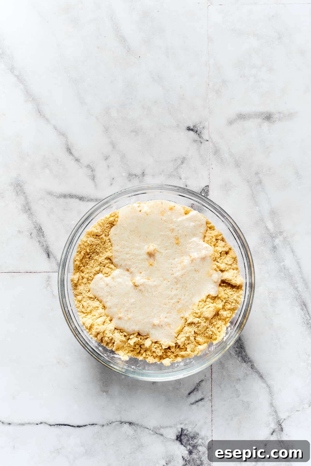 Buttermilk being mixed into biscuit dough.