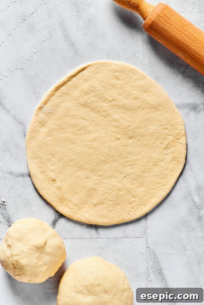 A piece of dough rolled into a thin, even circle on a floured work surface.