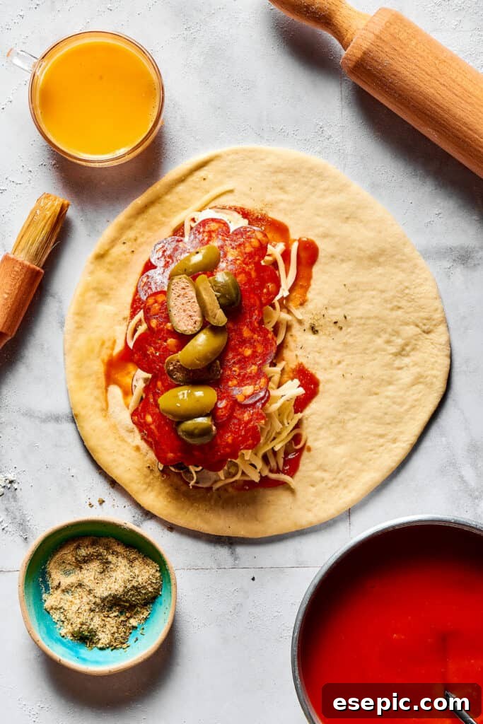 A dough circle with a thick layer of sauce, cheese, pepperoni, and other toppings on one half.
