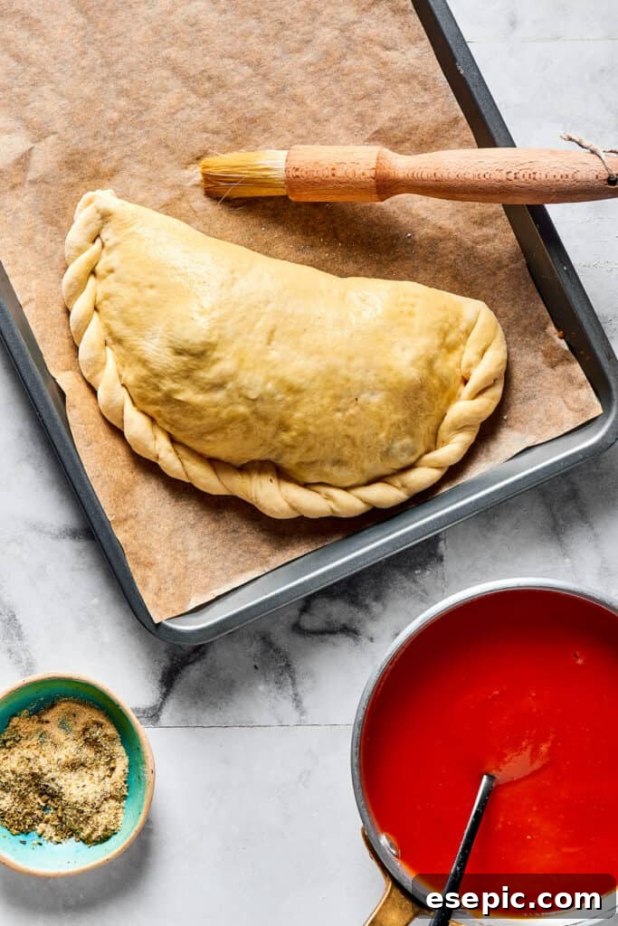 A folded calzone with perfectly crimped edges, ready for baking.