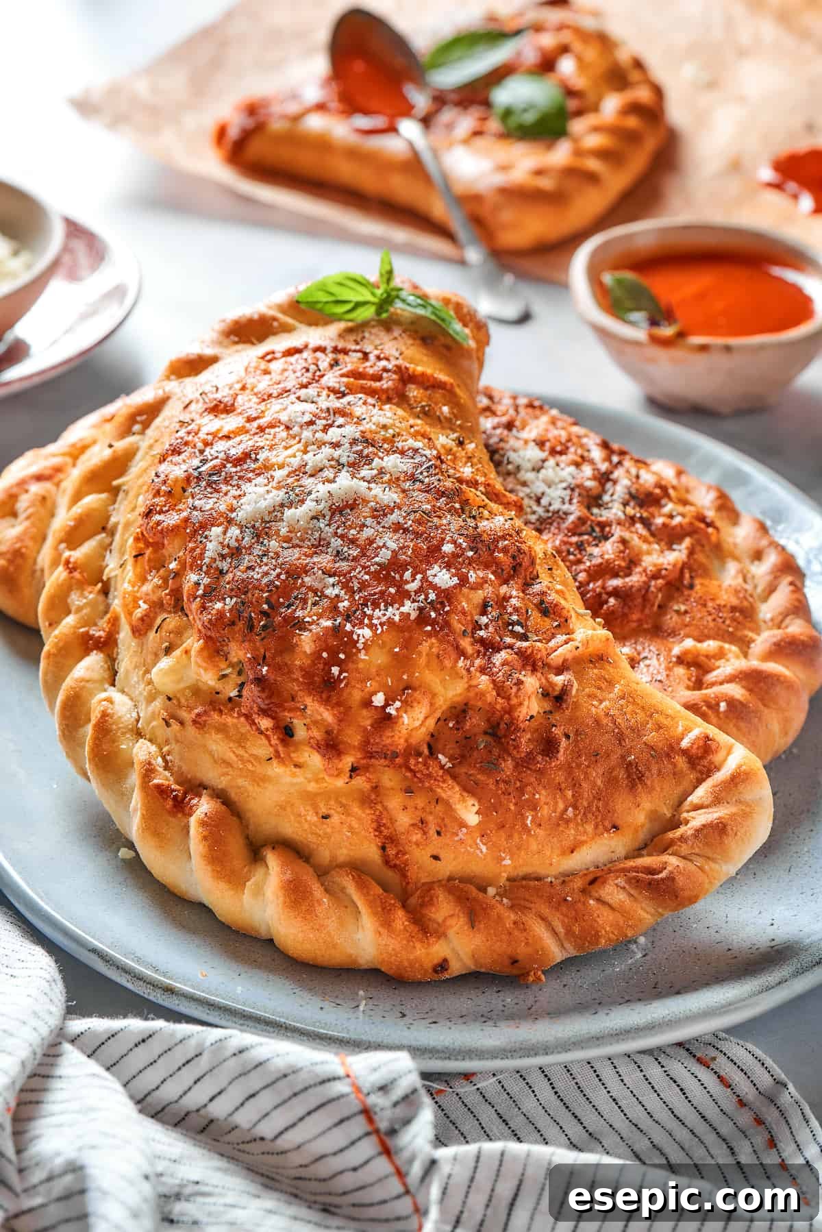 Two freshly baked pizza pockets with perfectly crimped edges, arranged neatly on a plate.