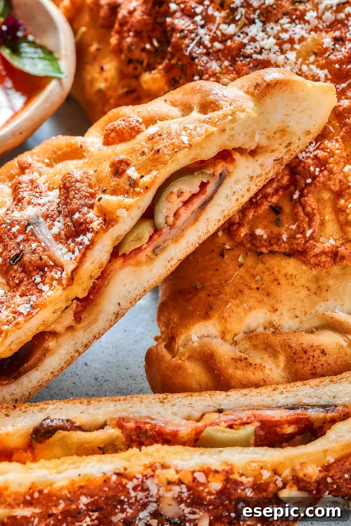 Close-up of the perfectly baked, golden-brown crust and melted cheesy interior of a halved pepperoni calzone.