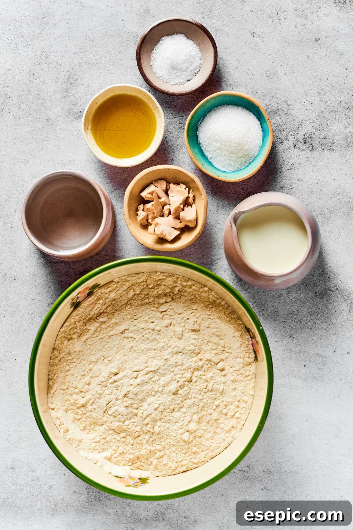 Various calzone dough ingredients laid out: Salt, olive oil, sugar, water, yeast, milk, and flour.