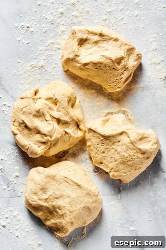 Dough portioned into 4 equal pieces on a floured work surface.