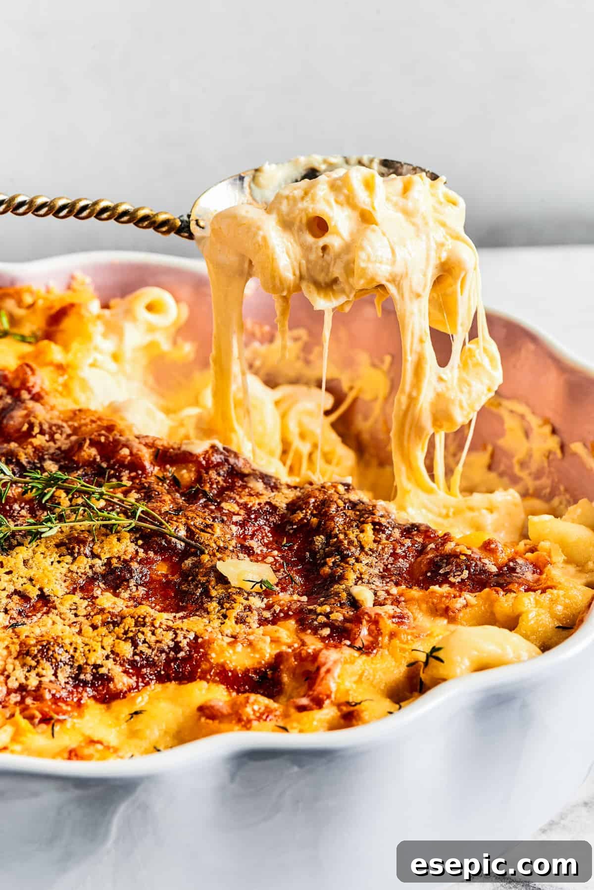 Lifting a spoonful of mac and cheese out of a fluted baking dish.