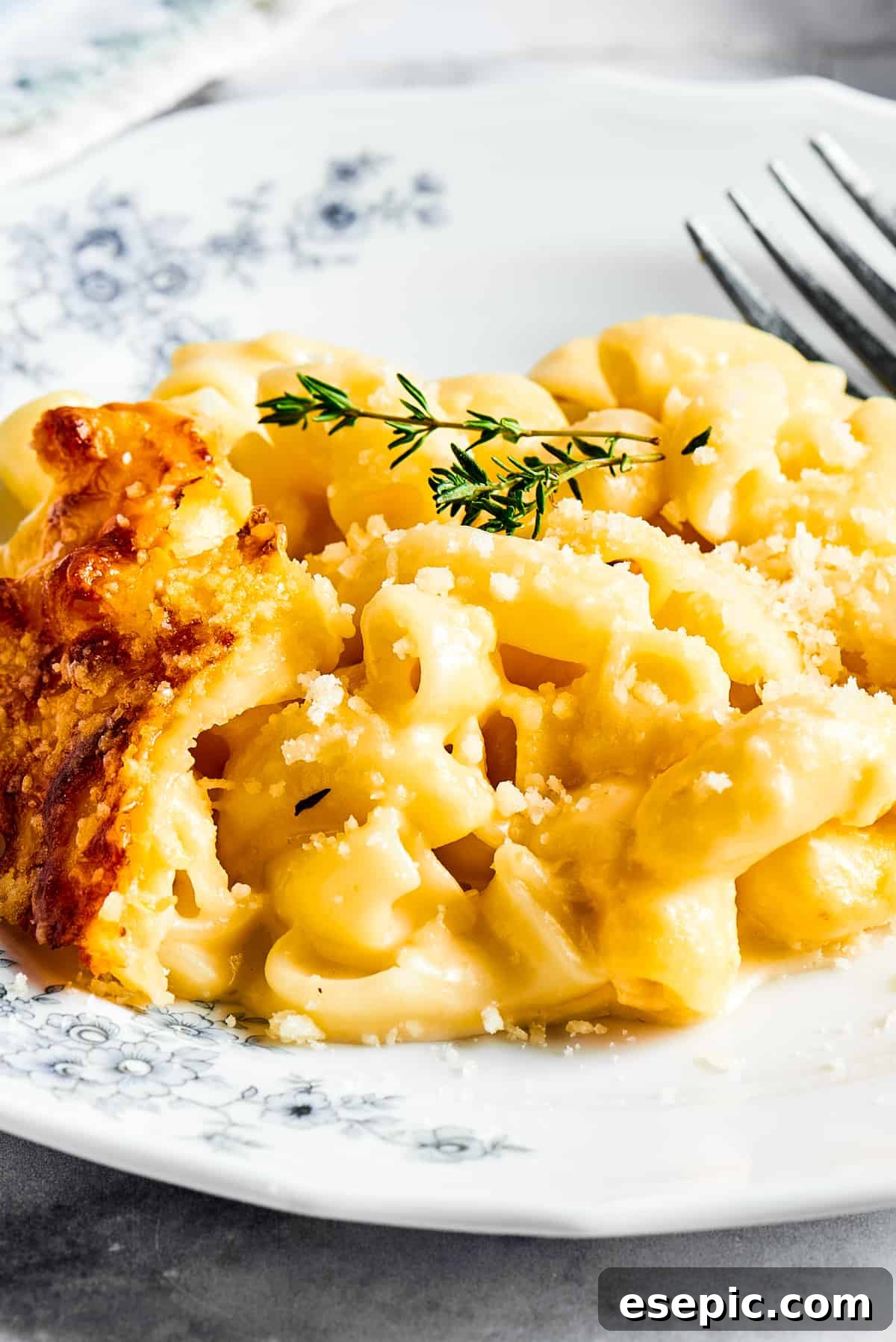 Macaroni and cheese garnished with fresh herbs on a flowered plate.
