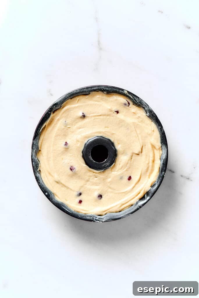 Sparkling Cranberry Christmas Pound Cake 5 A Bundt pan meticulously filled with smooth, ready-to-bake cake batter, promising a perfect shape.