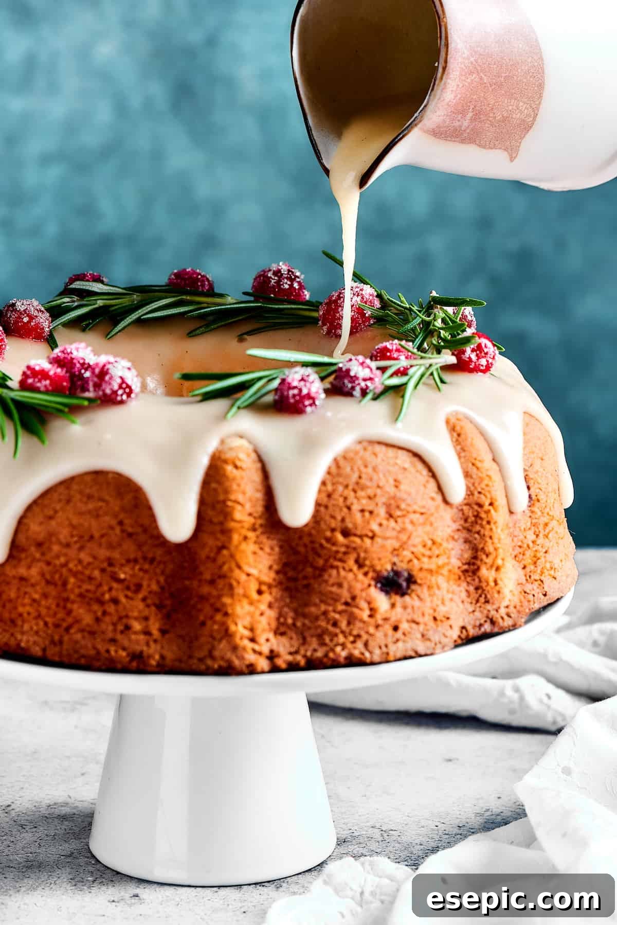 Christmas Cranberry Pound Cake is a festive holiday dessert with fresh cranberries, orange liqueur, vanilla bean paste, and a sweet glaze. The moment of truth: a thick, sweet orange glaze being generously poured over a perfectly golden Bundt cake.