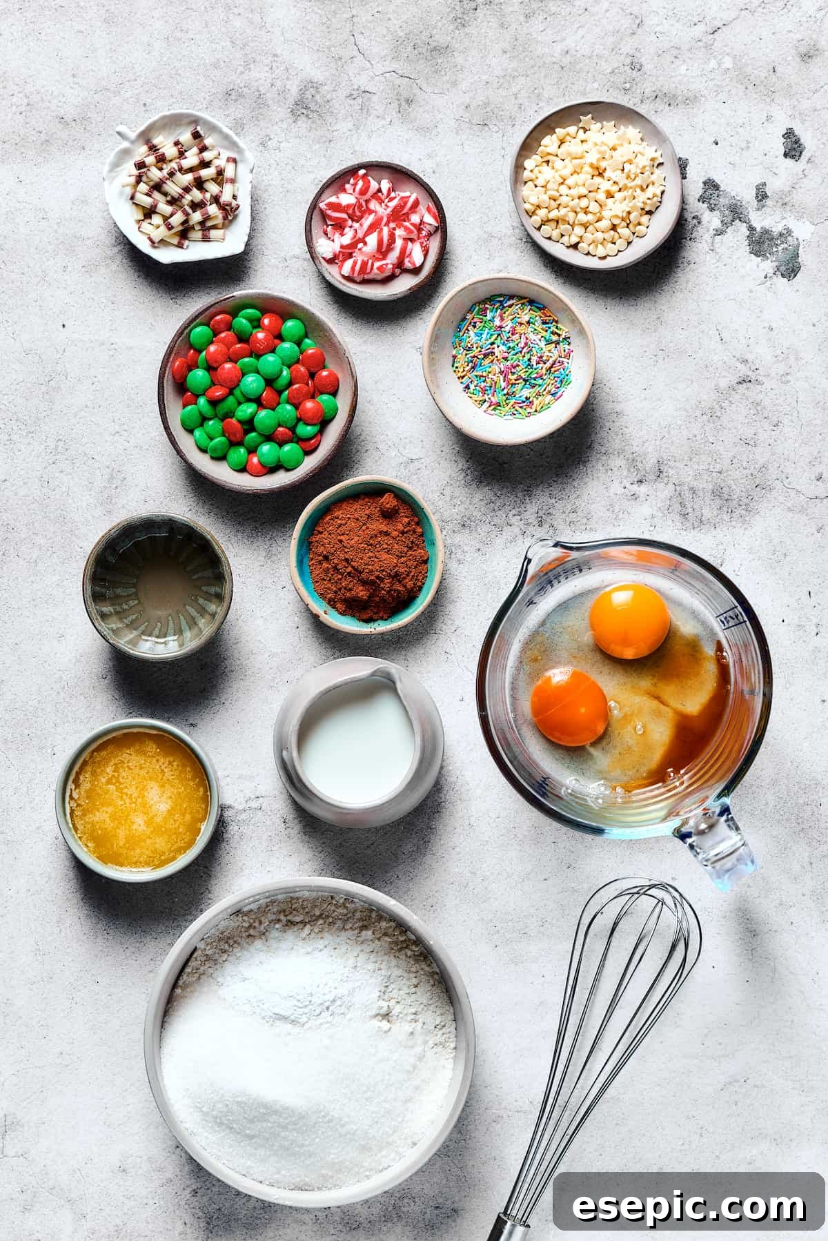 Easy vanilla and chocolate Christmas Cake Mix Cookies are studded with red and green M&Ms, and decorated with even more holiday goodies! All the essential ingredients for making delicious cake mix cookies neatly arranged on a rustic wooden table, showcasing a box of cake mix, eggs, butter, and colorful M&Ms.