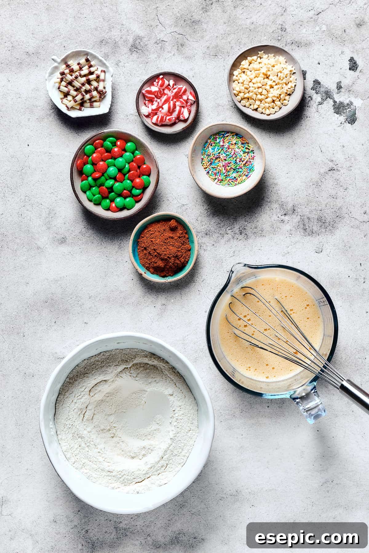 Yuletide Cake Mix Wonders 3 A visual guide showing cake mix cookie ingredients separated into bowls. Dry ingredients (cake mix, flour, sugar, baking powder, salt) are in one bowl, wet ingredients (eggs, butter, oil, milk, vanilla) in another. Cocoa powder, M&Ms, and other decorations are in small dishes.
