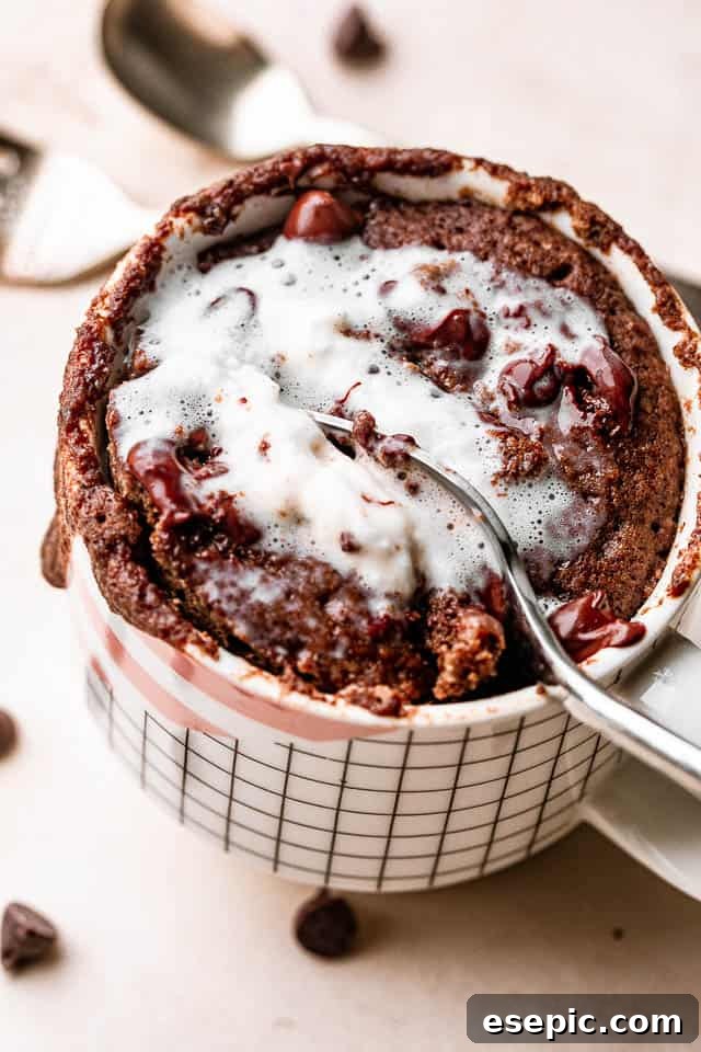 A rich chocolate mug cake topped with a generous swirl of whipped cream and chocolate shavings.