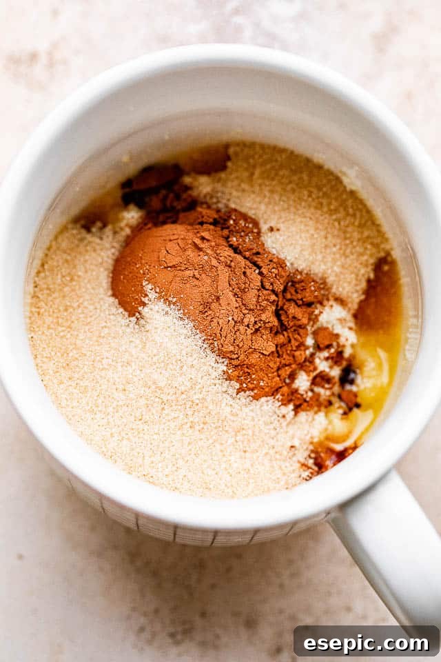 Cocoa powder, flour, and butter already in a mug, showcasing the dry ingredients added to the melted butter.