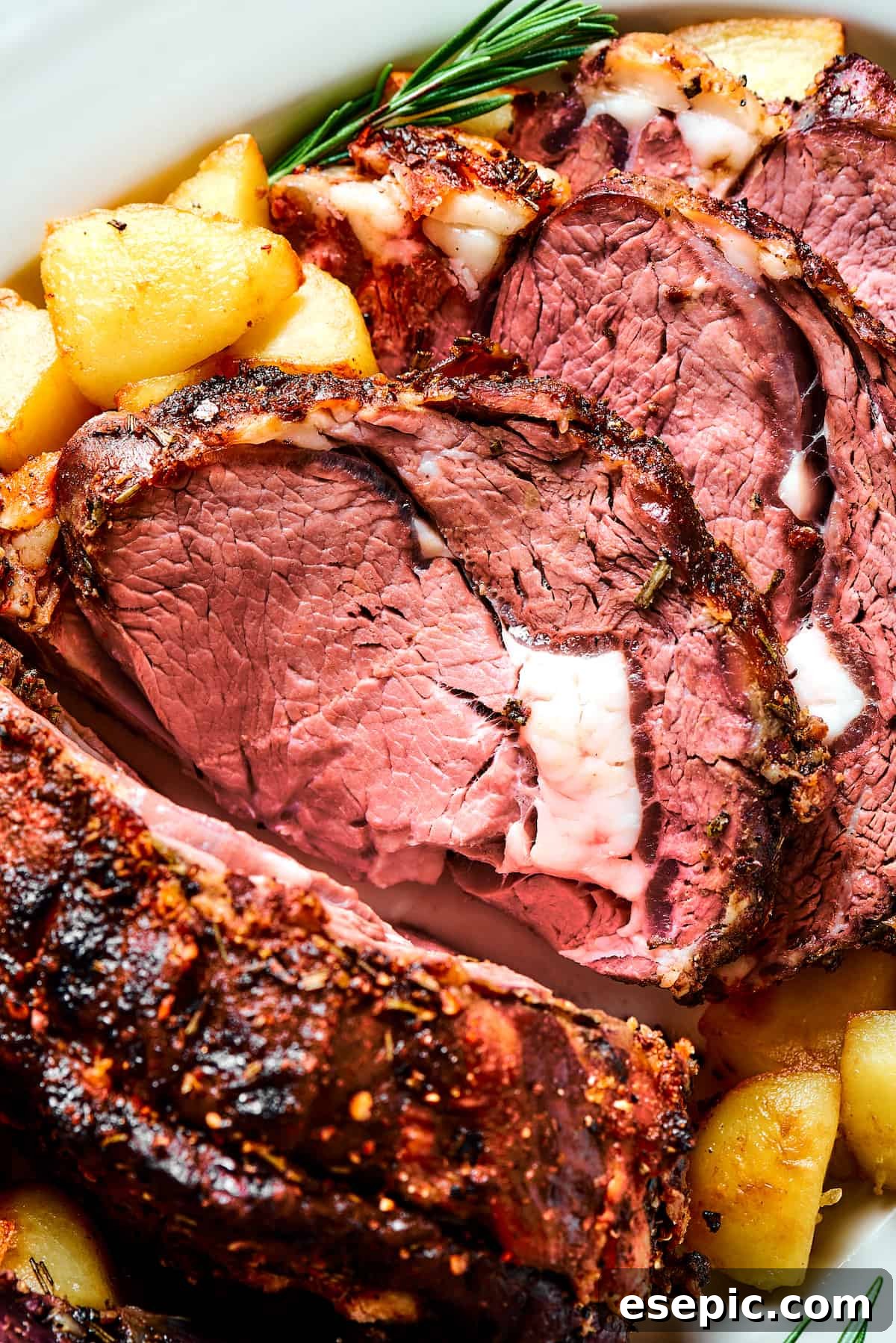 Perfectly sliced prime rib roast, garnished with fresh herbs, ready to be served.