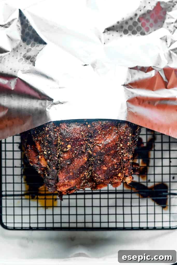A roasted prime rib covered loosely with aluminum foil for resting.