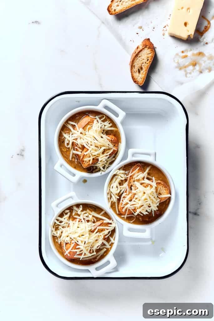 Mouth-watering individual bowls of French onion soup, fresh from the broiler with bubbly, golden-brown melted cheese over toasted baguette, ready to serve.