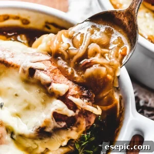 French Onion Soup topped with melted cheese and a golden-brown crouton, garnished with fresh thyme leaves.
