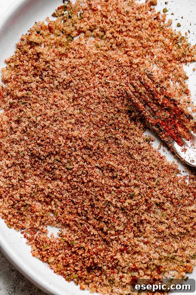 A bowl of homemade Cajun seasoning blend, featuring paprika, brown sugar, and various spices.