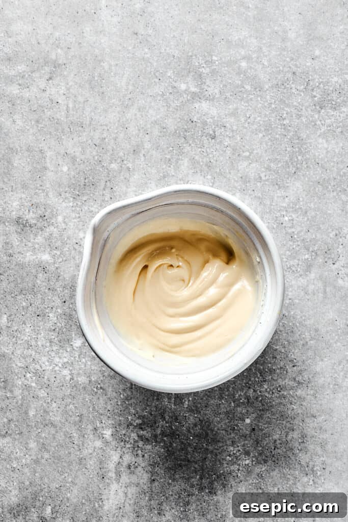 A pristine white mixing bowl filled with smooth, creamy cream cheese swirl mixture.