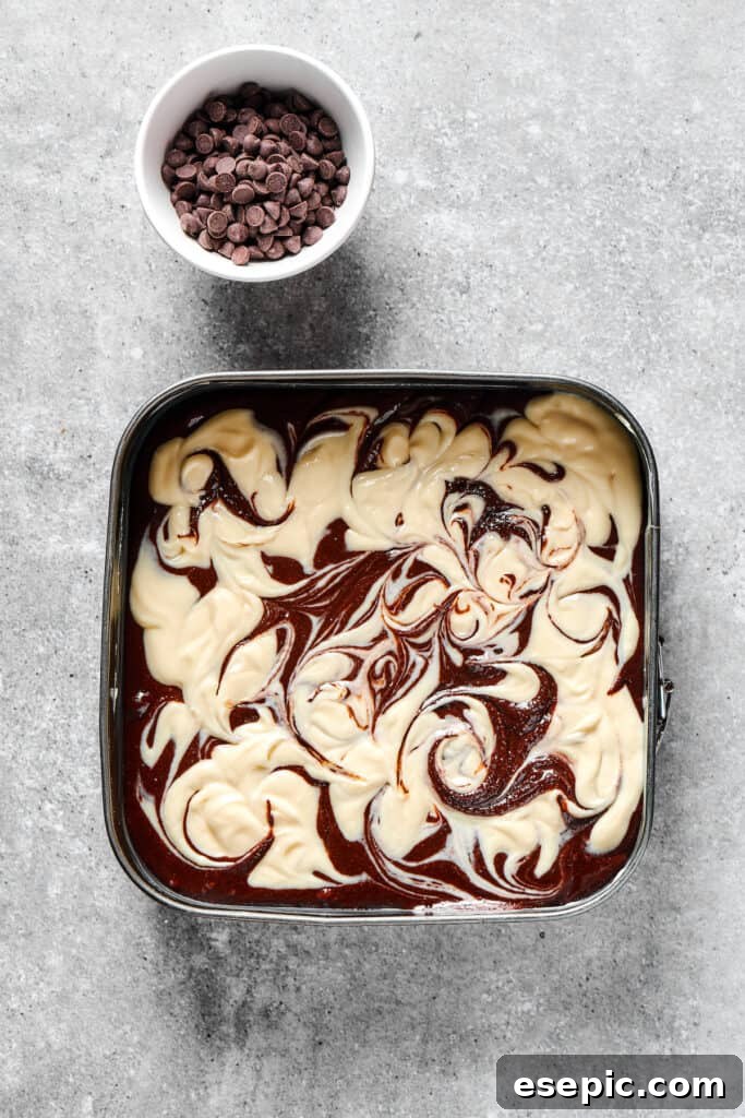 Unbaked cream cheese brownies with a distinct swirl pattern in a baking dish.